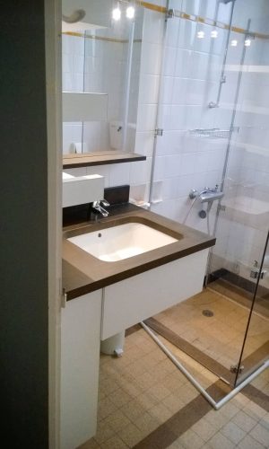 Agencement salle de bain en stratifié blanc structuré ; plan de toilette en béton ciré avec vasque en dessous.