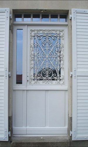 Porte d'entrée en chêne massif brun peint en blanc ; grille en récupération ; à ventail semi fixe et imposte fixe.